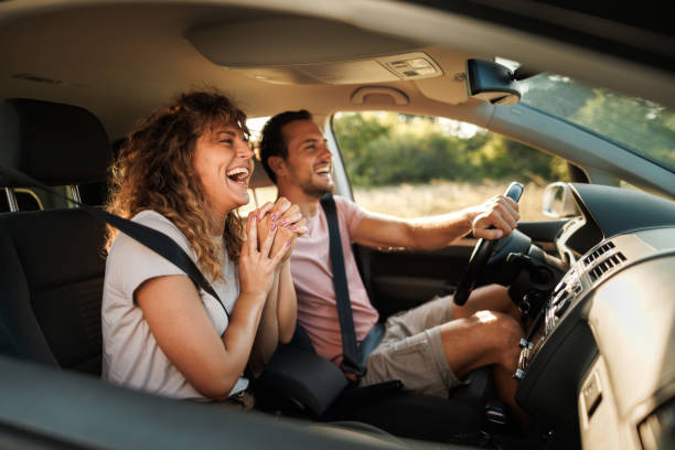 A couple laughing together inside a car on a road trip
