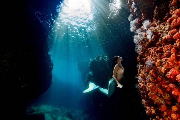 Sunlight streaming through an underwater cave with a serene figure